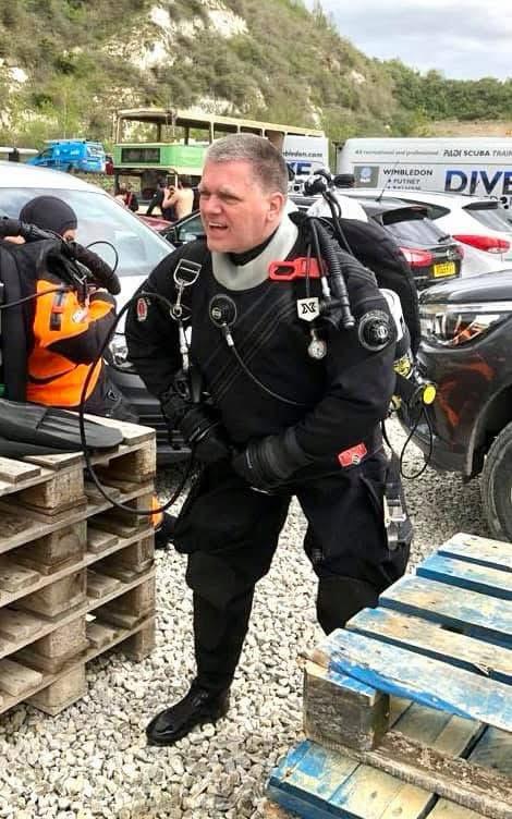 Diver kitting up in a dry suit and twinset in the car park at a UK inland dive site